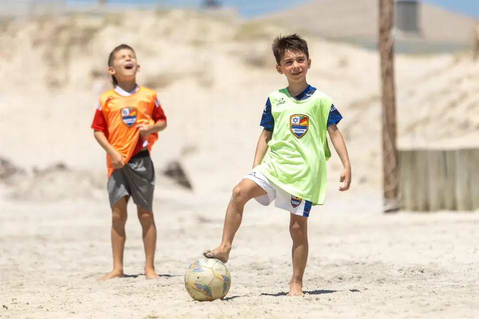 Crianças jogando bola na areia