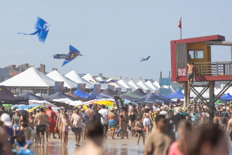 Público na praia com pipas